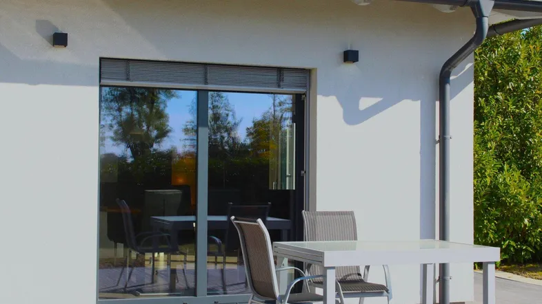 Moderne Terrasse mit Gartenmöbeln und Zugang zum Haus, ideal für entspannte Stunden im Freien.