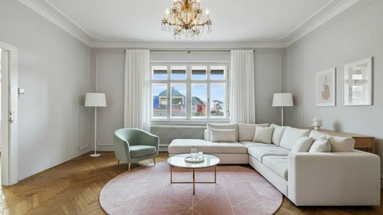 Helles Wohnzimmer mit Fischgrätparkett, Stuckdecke und modernem Sofa in eleganter Atmosphäre.