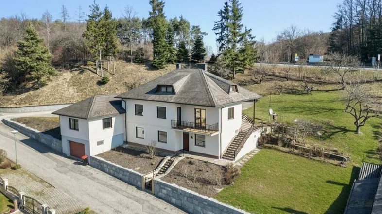 Großzügiges Einfamilienhaus mit Satteldach und angrenzender Garage in ländlicher Umgebung.