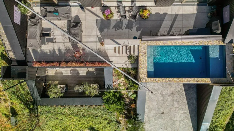 Luftaufnahme des modernen Hauses mit großzügiger Terrasse, Pool und gepflegtem Gartenbereich.