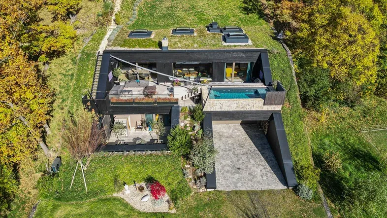 Luftaufnahme eines modernen Hauses mit Gründach, Pool und weitläufigem Garten.