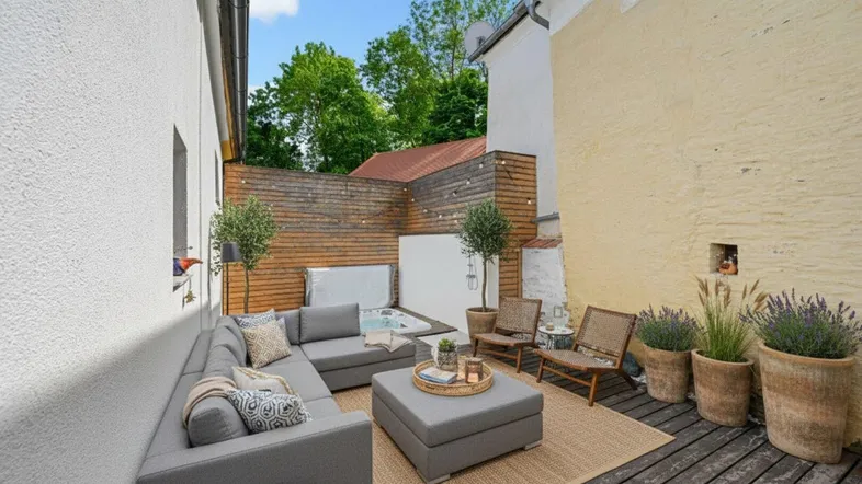 Gemütliche Terrasse mit Lounge-Möbeln, Whirlpool und Holzwänden für Privatsphäre.