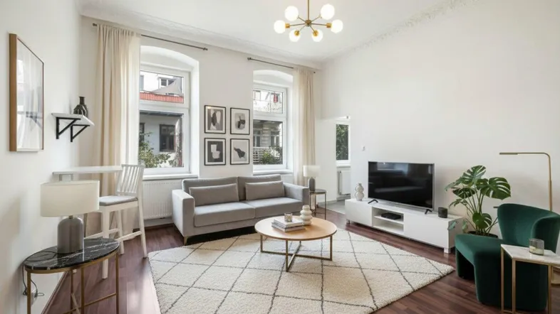 Helles Wohnzimmer mit modernem Mobiliar, Parkettboden und Stuckdecke.