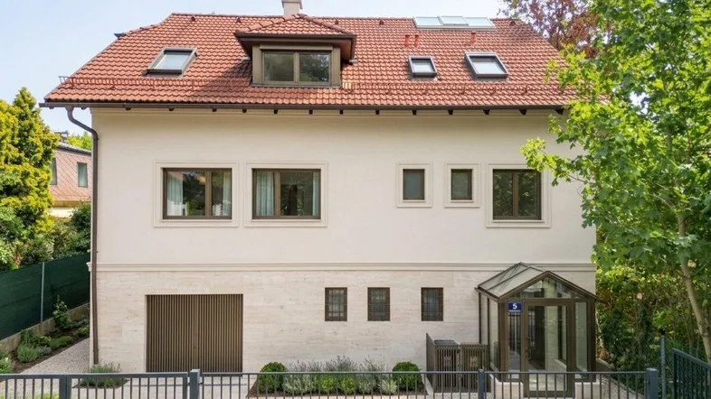 Vorderansicht eines renovierten Hauses mit Satteldach, Garage und gepflegtem Vorgarten.