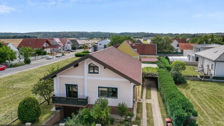 Luftaufnahme eines Einfamilienhauses mit Vorgarten, Zufahrt und Blick auf die ländliche Umgebung.