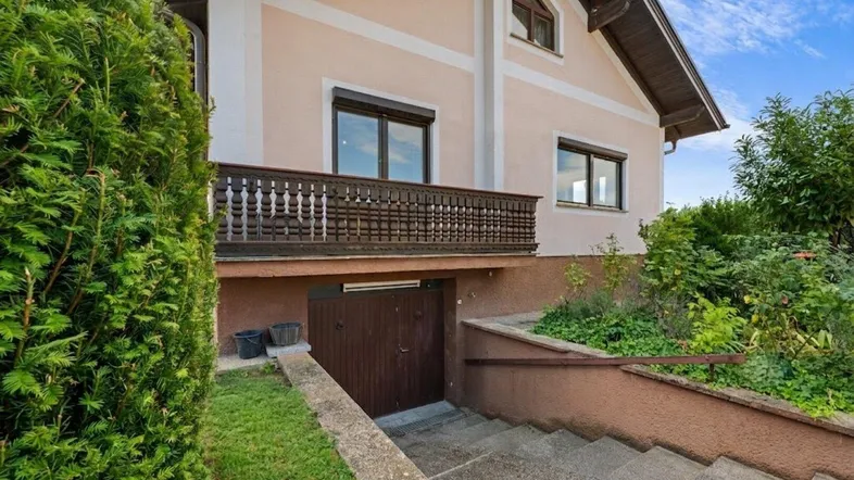 Seitenansicht des Hauses mit Zugang zum Kellergeschoss und einem kleinen Balkon.