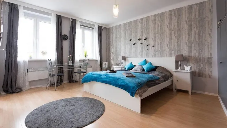 Helles Schlafzimmer mit Holzboden, gemusterter Wand und kleinem Essbereich, modern eingerichtet.