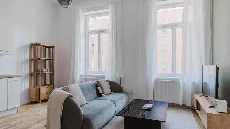 Helles Wohn- und Esszimmer mit moderner Couch, Holzboden und großen Fenstern.