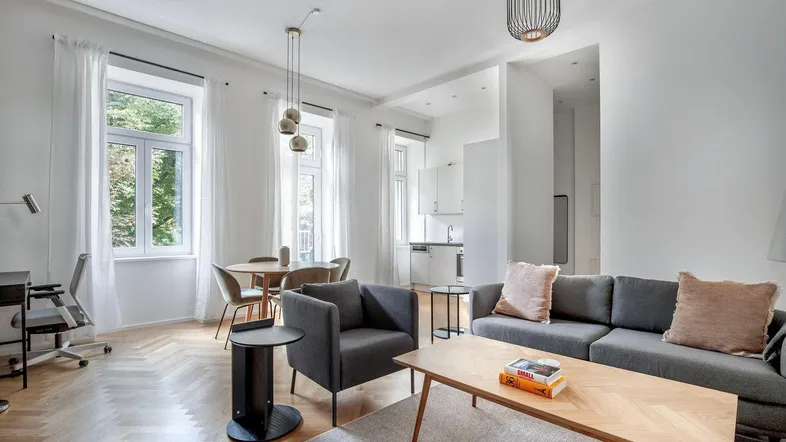 Helles, offenes Wohn- und Esszimmer mit Fischgrätparkett und moderner Einrichtung, inklusive Arbeitsbereich.