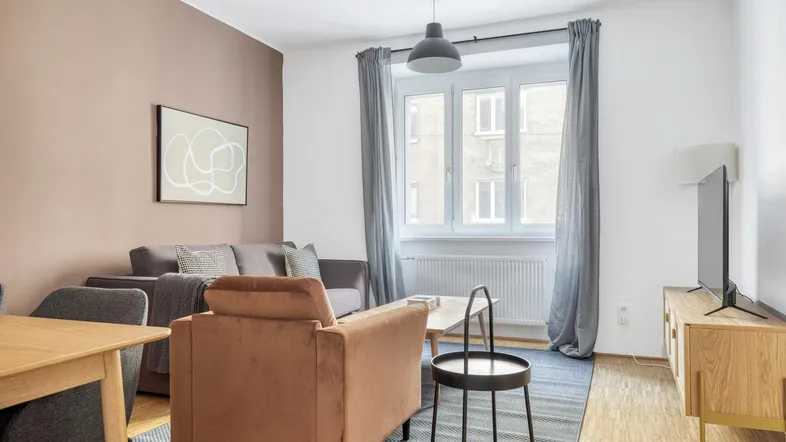 Helles Wohn- und Esszimmer mit modernem Mobiliar, Parkettboden und Blick auf die Straße.