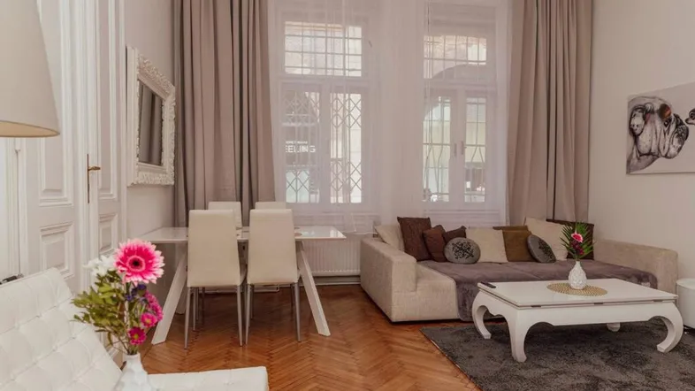 Helles Wohn- und Esszimmer mit Fischgrätparkett, beigem Sofa und einem Esstisch für vier Personen.