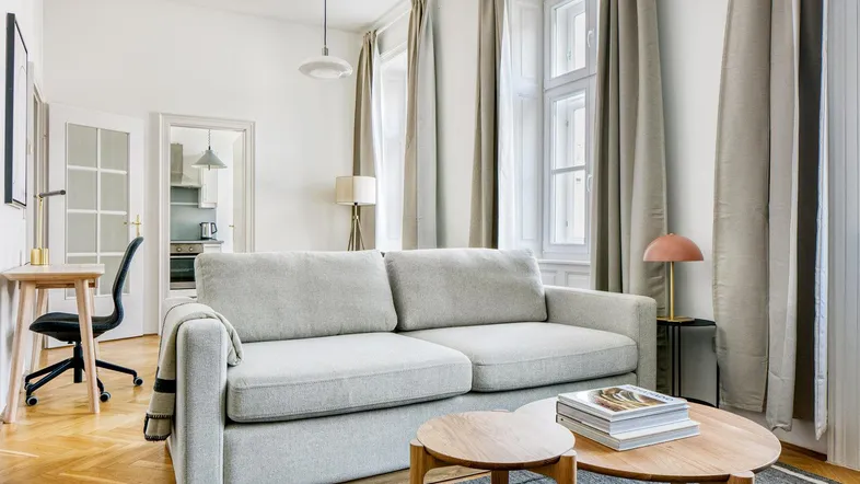 Helles Wohnzimmer mit bequemem Sofa, Holzboden und Blick auf die Fenster.