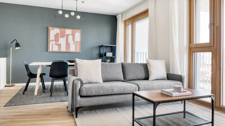 Modernes Wohn- und Esszimmer mit Holzboden, grauer Couch und stilvoller Dekoration.