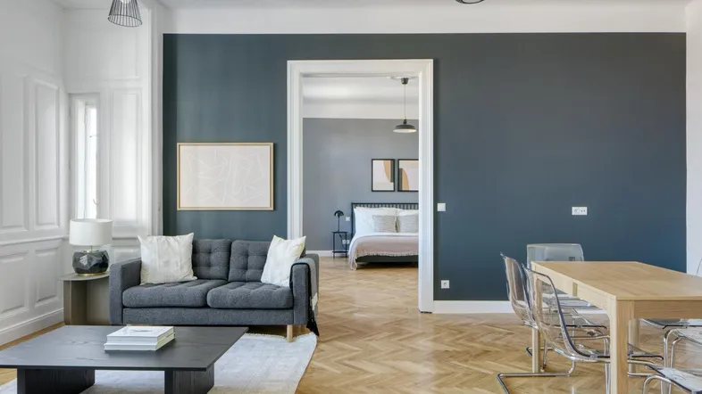 Geräumiger Wohn-Essbereich mit modernem Sofa, Esstisch und Parkettboden, offen zum Schlafzimmer.