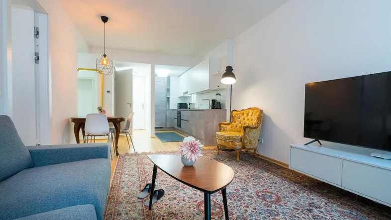 Gemütlicher offener Wohn- und Essbereich mit Teppichboden, Sofa und Blick zur modernen Küche.