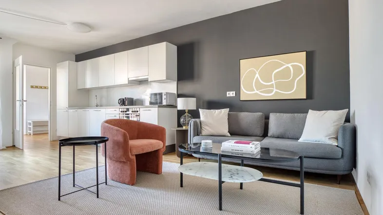 Moderner offener Wohnbereich mit integrierter Küche, grauem Sofa und Akzentwand.