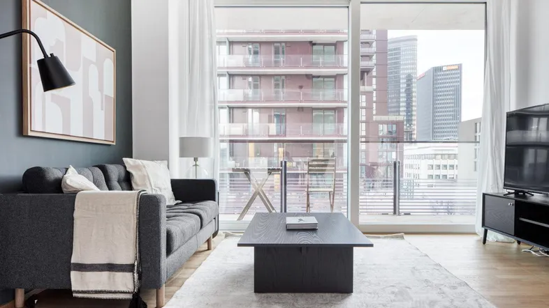 Helles Wohnzimmer mit modernem Sofa, Couchtisch und großem Fenster mit Stadtblick.