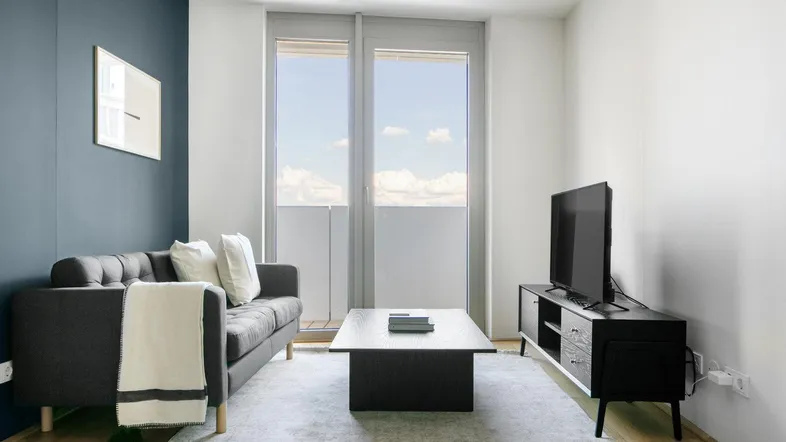 Helles Wohnzimmer mit modernem Sofa, Couchtisch und Zugang zum Balkon.