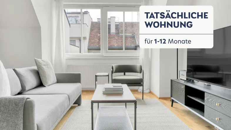 Helles Wohnzimmer mit gemütlichem Sofa, Couchtisch und Blick auf die Dächer der Stadt.