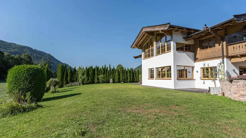 Großzügiger Gartenbereich mit gepflegtem Rasen und Blick auf die umliegende Berglandschaft.
