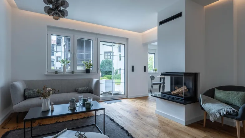 Helles Wohnzimmer mit modernem Kamin, Holzboden und Zugang zu einem Außenbereich.