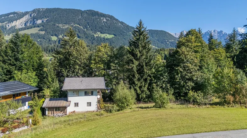 Charmantes Haus in idyllischer Berglandschaft mit weitem Blick über grüne Wiesen und Wälder.