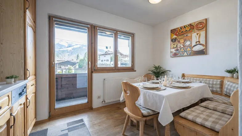 Gemütlicher Essbereich mit Holzeinbauten, Bergblick und Zugang zum Balkon.