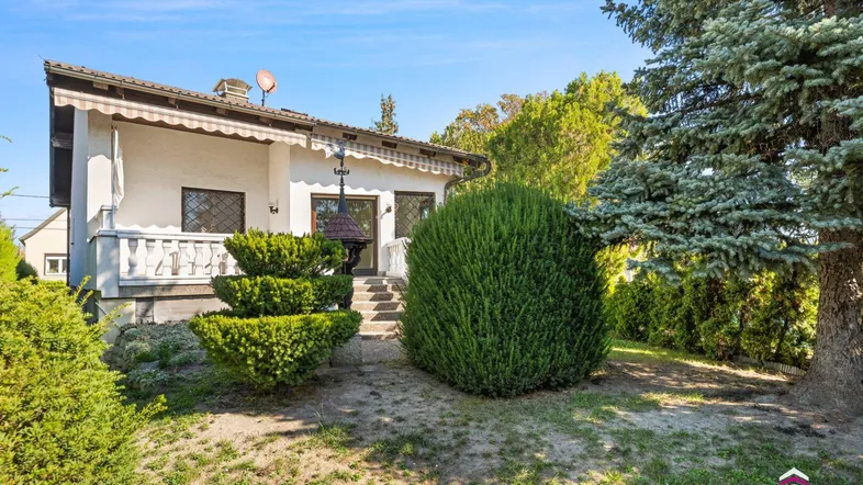 Einfamilienhaus mit gepflegtem Gartenbereich und Terrasse unter blauem Himmel.