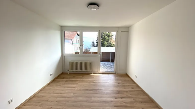 Helles Zimmer mit Laminatboden und Zugang zu einem sonnigen Außenbereich.