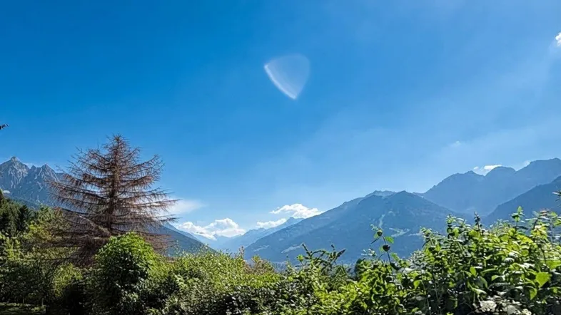 Panoramablick auf die majestätischen Berge mit üppiger grüner Vegetation unter einem strahlend blauen Himmel.