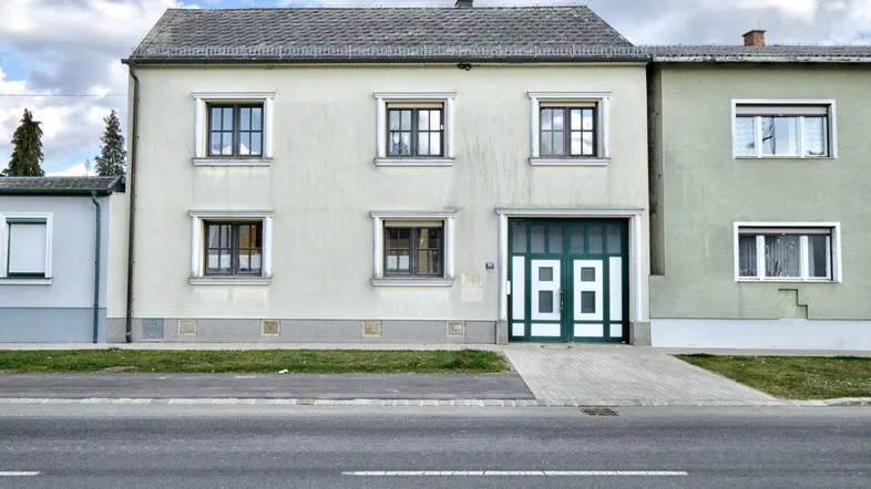 Fassade eines Wohnhauses mit Garage und Fenstern, direkt an einer Straße gelegen.