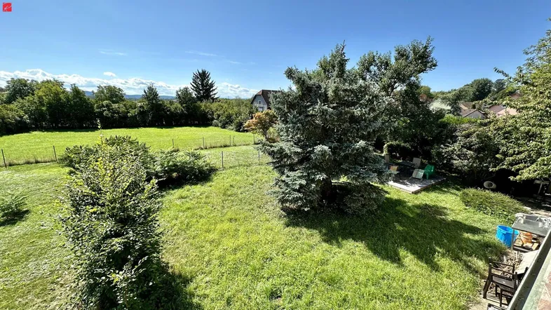 Weitläufiger Gartenbereich mit grüner Wiese, Bäumen und Blick in die Landschaft.