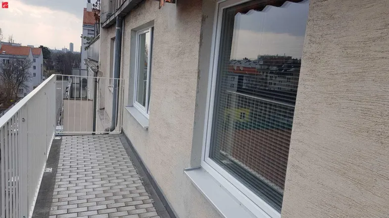 Balkon mit Pflastersteinen und Metallgeländer bietet einen Blick auf die umliegende Stadt.