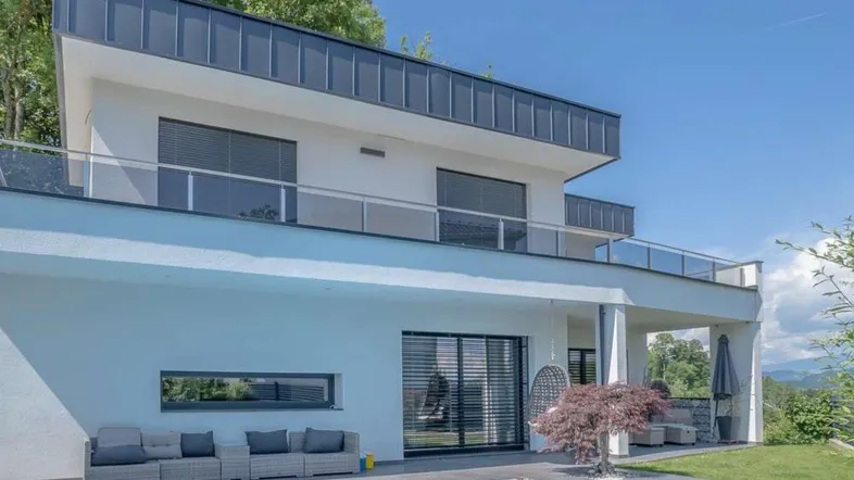 Moderne Villa mit Pool, Terrasse und Bergblick unter blauem Himmel.