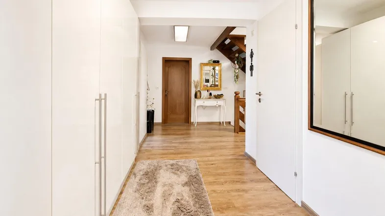 Heller Flur mit integrierten weißen Schränken, Holzfußboden und Zugang zur Treppe.
