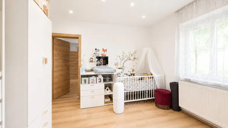 Helles Kinderzimmer mit Babybett, Wickeltisch und freundlicher Wanddekoration, ideal für kleine Kinder.