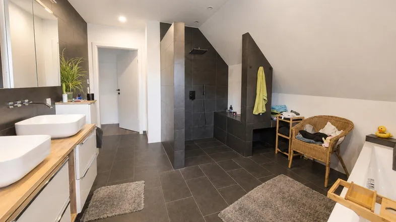 Modernes Badezimmer mit Doppelwaschbecken, großer begehbarer Dusche und Badewanne unter Dachschräge.