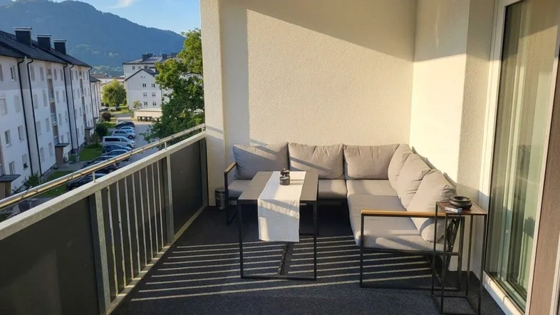 Heller Balkon mit bequemen Outdoor-Möbeln und Blick auf die umliegende Berglandschaft.