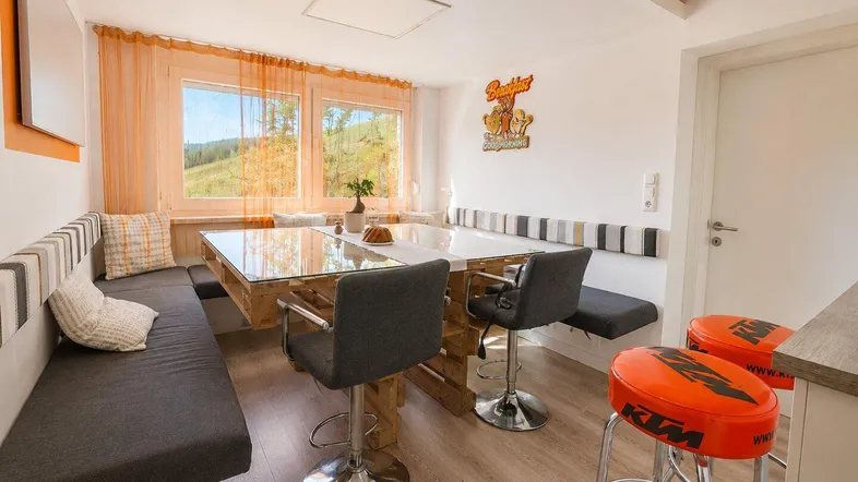 Gemütlicher Essbereich mit Holztisch, gepolsterten Bänken und weitem Blick in die Natur.