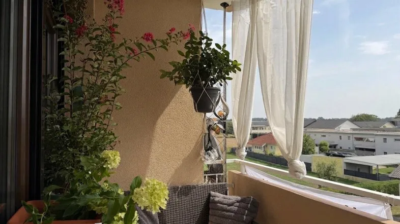 Gemütlicher Balkon mit Pflanzen, Sitzgelegenheiten und weitem Blick über die Umgebung.