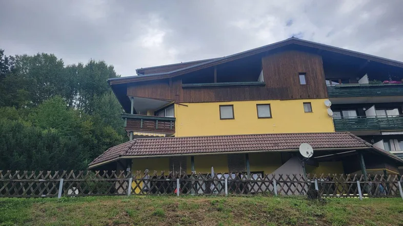 Traditionelles Gebäude im Chalet-Stil mit gelber Fassade, Holzelementen und mehreren Balkonen.