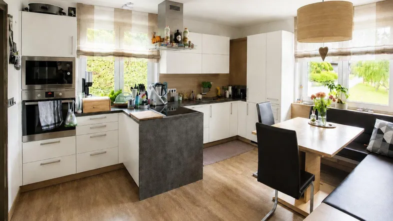 Helle, moderne Wohnküche mit integriertem Essbereich, Holzboden und Blick ins Grüne.