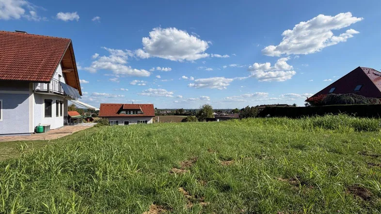 Weitläufiges Grundstück mit grüner Wiese und Blick auf die umliegende Landschaft und Häuser.