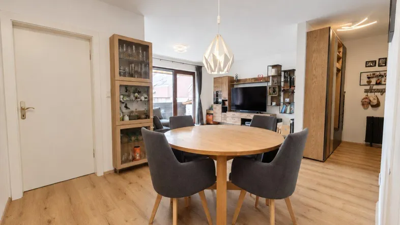 Heller Wohn- und Essbereich mit Holzboden, rundem Esstisch und Zugang zum Wohnzimmer.