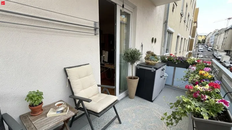 Gemütlicher Balkon mit Sitzgelegenheiten, Blumenkästen und Blick auf die Straße.