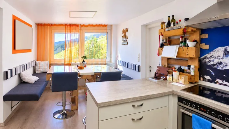 Moderne Küche mit Essbereich, Holzelementen und einem weiten Blick auf die umliegende Berglandschaft.
