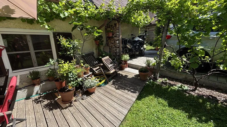 Holzterrasse mit üppiger Begrünung und gemütlichen Sitzgelegenheiten, ideal für entspannte Stunden im Freien.