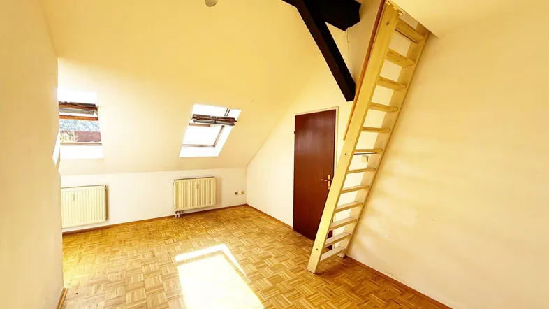 Helles Dachzimmer mit Parkettboden, Dachfenstern und einer Holzleiter zum oberen Bereich.