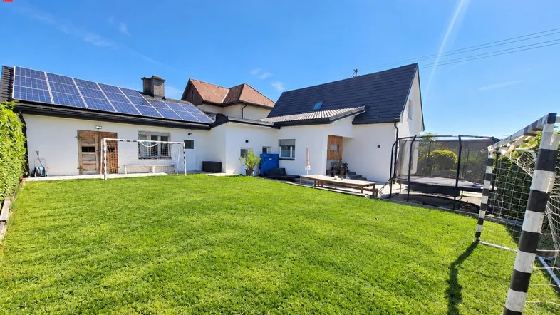 Großzügiger Gartenbereich mit Rasenfläche, Trampolin und Fußballtoren, umgeben von einem modernen Einfamilienhaus mit Solaranlage.