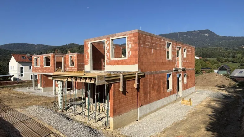 Rohbau von zwei modernen Reihenhäusern in sonniger Lage mit Blick auf die umliegende Landschaft.